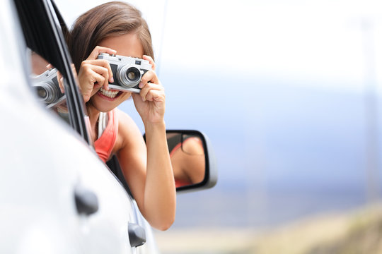 Woman tourist taking photo in car with camera