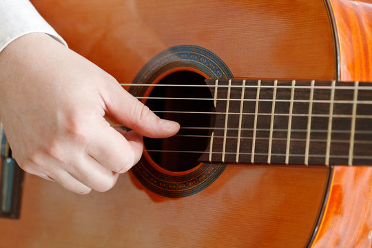 male hand plays on acoustic guitar