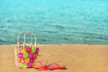 Fototapeta na wymiar Slippers with wicker bag on the beach