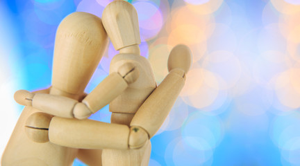 wooden figures of child hug parent embrace,beautiful blue bokeh