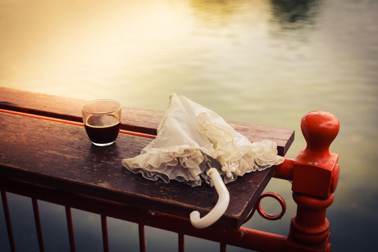Coffee and umbrella on table by the lake