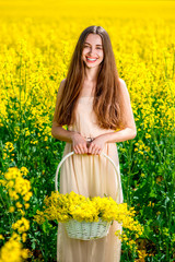 Naklejka na ściany i meble Beautiful girl holding the basket full of the yellow flowers