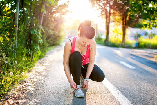 Portrait of active joggin woman resting and preparing shoes