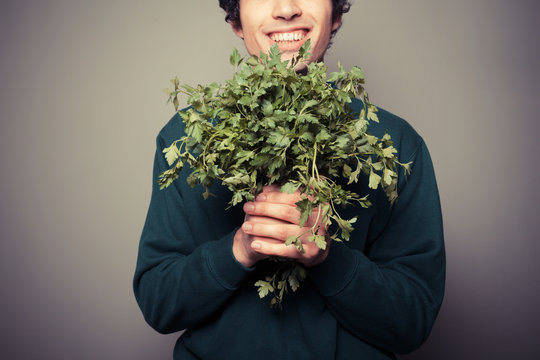 Happy young man with a big bunch of parsley