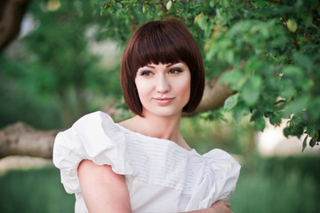 Beautiful girl standing in greens near the tree