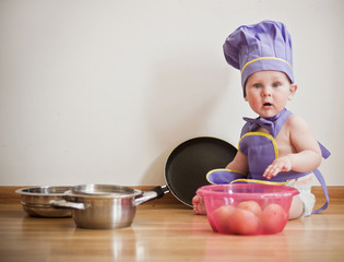 Little boy in a chief hat sitting on a floor
