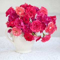 bright bouquet of a beautiful tea roses in a ceramic jug