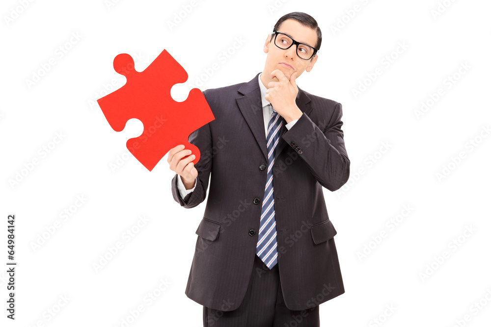 Wall mural Pensive businessman holding a piece of puzzle