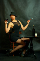 Fototapeta Kobieta z papierosem i kieliszkiem wina przy stoliku obraz