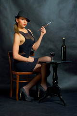 Fototapeta Piękna kobieta trzymająca papierosa przy stoliku. obraz