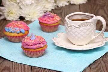 Bright colored muffins with tea and flowers