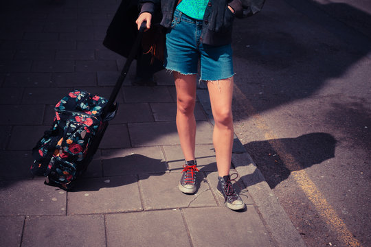 Young woman standing in the street with a suitcase