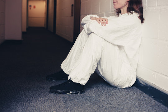 Upset woman in boiler suit sitting in corridor