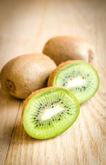Kiwi on the wooden background: whole fruit and cross section