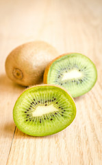Kiwi on the wooden background: whole fruit and cross section