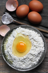 Wheat flour in metal bowl and eggs