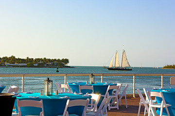 A sea view of dining area with sailboat passing by.