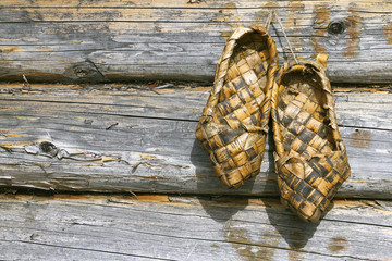 Russian bast shoes and wooden wall