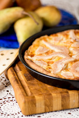 Pizza pere e brie nella teglia sul tagliere di legno
