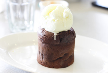 Chocolate cake with ice cream on top on white plate