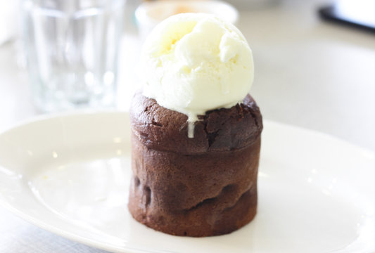 Chocolate cake with ice cream on top on white plate