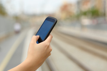 Woman hand holding a smart phone in a train station