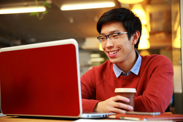 Happy asian man in glasses working on laptop