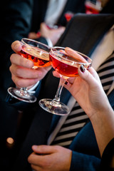 Hands of man and woman cheering with glasses of pink champagne