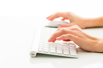 Hands of a person working an a keyboard over white background
