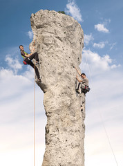 Climbers in action, young woman and man climbing difficult rock.