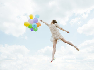 Magic lovely girl flying in the sky with balloons
