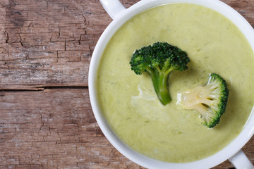 Cream soup of broccoli on the old table macro top view