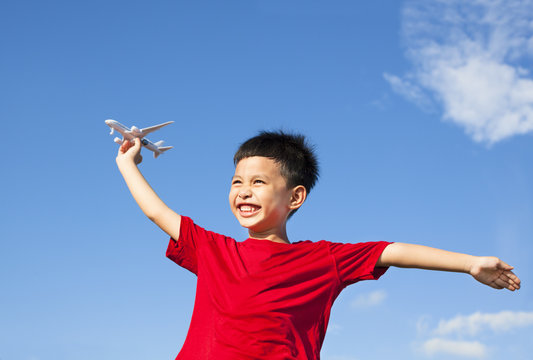 happy boy holding a airplane toy with blue sky background