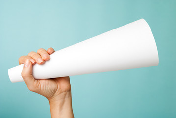 Hand up holding a white blank megaphone on blue background.