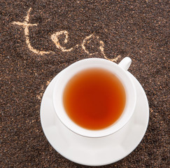 A cup of tea with the word TEA written on the dried tea leaves