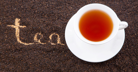 A cup of tea with the word TEA written on the dried tea leaves