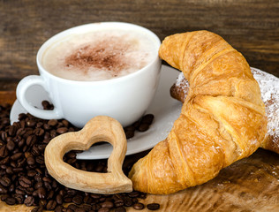 Cup of cafe latte and coffee beans on old wooden board