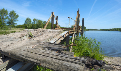 Fototapeta na wymiar Obsolete bridge on the shore of a lake