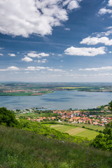 Spring countryside with village, lake, blue sky and clouds
