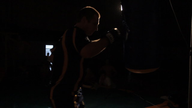 Aggressive strong muscular boxer beats the punching bag in