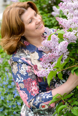 Middle-aged woman near blossoming lilac