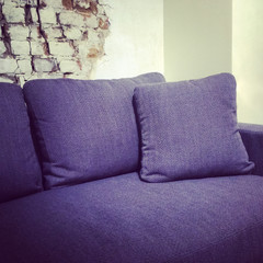 Blue textile sofa near brick wall