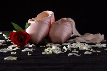 Old used ballet slippers lying on floor with rose and petal © Alta Oosthuizen