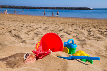 Fototapeta na wymiar bucket with plastic beach toys in sand on sea shore