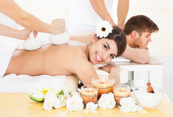 Obraz na płótnie Canvas Woman Receiving Massage With Herbal Compress Stamps