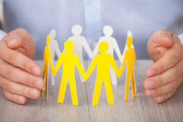 Hands Protecting Team Of Paper People