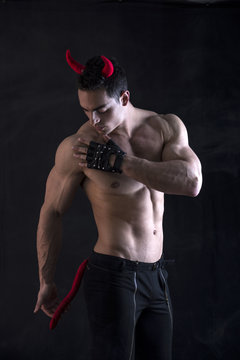 Shirtless muscular male bodybuilder dressed with devil costume