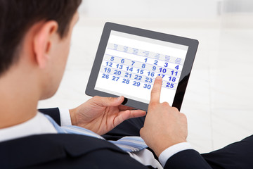 Businessman Using Calendar On Digital Tablet In Office