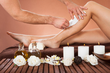 Obraz na płótnie Canvas Therapist Waxing Customer's Leg At Beauty Spa
