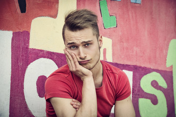 Attractive young blond man against colorful graffiti wall
